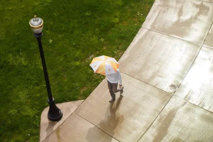 photo of student walking in rain